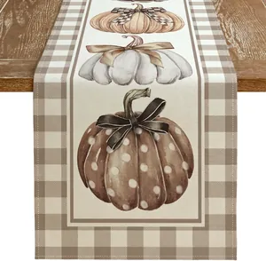 Détail du chemin de table automnal en lin avec motifs de citrouilles et bordure écossaise