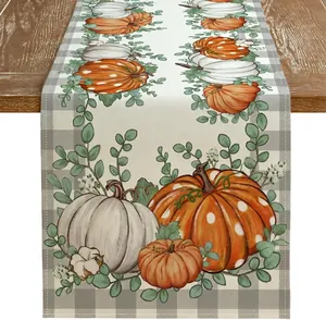 Détail d'un chemin de table d'automne rustique avec citrouilles et feuilles d'eucalyptus en lin