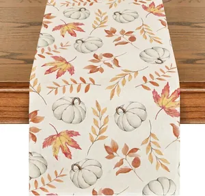 Détail d'un chemin de table d'automne en lin avec motifs citrouilles blanches et feuilles d'érable