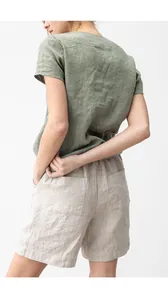 Rückansicht eines salbeigrünen Baumwoll-Leinen-T-Shirts und beige Freizeithose am Modell.