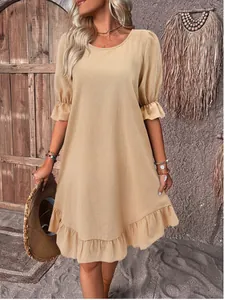 Vintage beige cotton linen dress with puff sleeves and ruffled hem shown on model