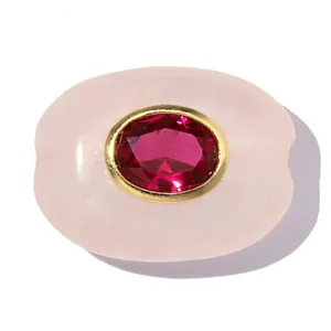 Detailansicht einer ovalen Rosenquarz-Perle mit rotem Edelstein und 18k Vergoldung.