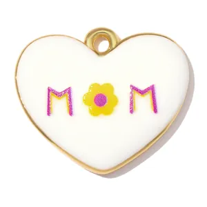 Nahaufnahme eines herzförmigen 'MOM'-Emaille-Anhängers mit gelber Blume und Goldbeschichtung