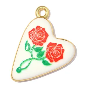 Detailaufnahme eines herzförmigen Anhängers mit rotem Rosenmotiv und 18k Goldbeschichtung.