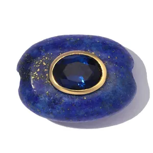 Nahaufnahme einer ovalen Lapislazuli-Perle mit zentralem blauen Edelstein im Goldrand.