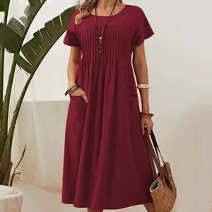 Woman in a dark red cotton linen midi dress with pleated details and side pockets