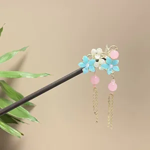 Detail of traditional Chinese wooden hair stick with blue flowers and pink beads tassels.