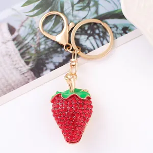 Vista macro dettagliata di un portachiavi a fragola con strass rossi e anello in oro
