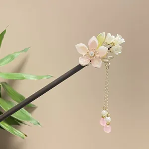 Detailed macro shot of elegant wooden hairpin with pink shell flower and dangling tassel