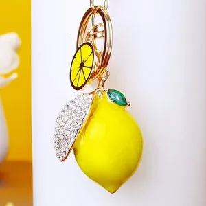 Zoom sur un porte-clés citron jaune avec strass, feuille en métal et charm fruité.