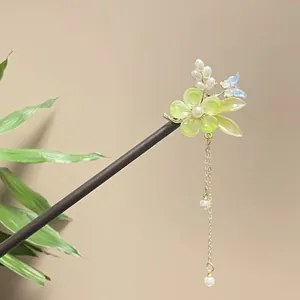 Detailed view of traditional Chinese sandalwood hair stick with green flower and tassel