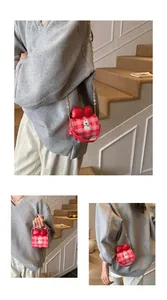 Detail view showing a mini pink checkered crossbody bag with red bow and cartoon dog print