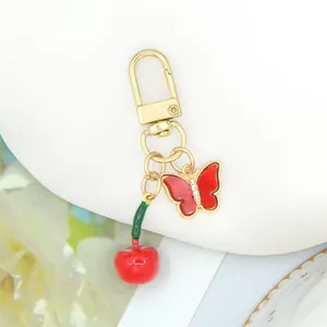 Primo piano di un portachiavi decorativo con ciliegia rossa e farfalla con strass scintillanti.