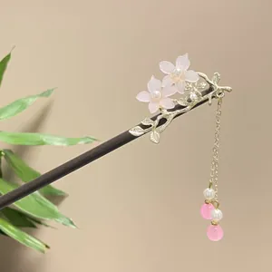 Close-up of elegant wooden hair stick decorated with pink flowers and gold tassel detail