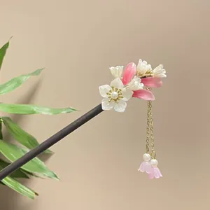 Detailed view of an ancient style sandalwood hair stick with pink floral tassels.
