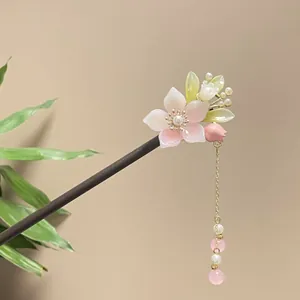 Detailed view of a handmade floral wooden hair stick featuring an elegant pink tassel