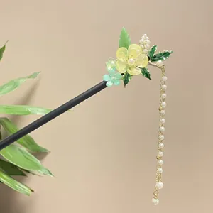 Macro view of elegant wood hair stick with delicate flower charms and pearl tassels