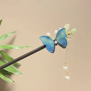 Macro view of blue embroidered butterfly and pearl tassels on a sandalwood hair stick