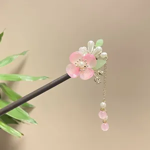 Detailed view of handmade pink flower and pearl tassel on a sandalwood hair stick