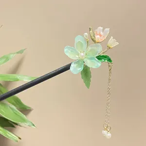 Detailed view of a traditional Chinese sandalwood hair stick with green floral tassel.