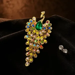 Détail macro d'une broche paon de style vintage avec strass colorés et pierre verte.