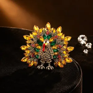 Détail d'une broche dinde sertie de cristaux jaunes et verts sur fond de velours noir