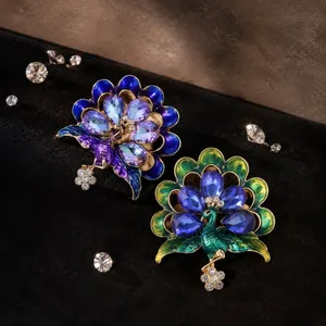 Vue détaillée de deux broches paon avec cristaux étincelants et finition émail