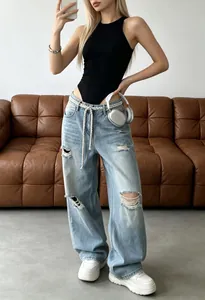 Sleeveless black bodysuit paired with light blue ripped jeans in a stylish home setting