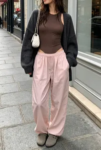 Model wearing a brown sleeveless bodysuit with pink pants in a chic street setting