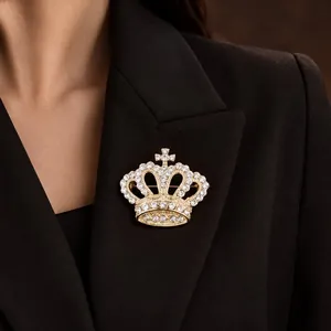 Elegant gold crown brooch with sparkling white rhinestones pinned to a black suit lapel