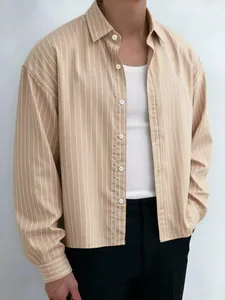 Detail view of men's loose khaki vertical striped shirt layered with a white tank top