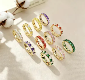 Detailansicht bunter Eternity-Ringe mit dreieckigen Zirkonia-Steinen auf beigem Stoff