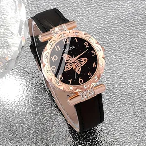 Detailansicht einer eleganten Damenuhr mit schwarzem Sternenzifferblatt und goldenem Schmetterling.