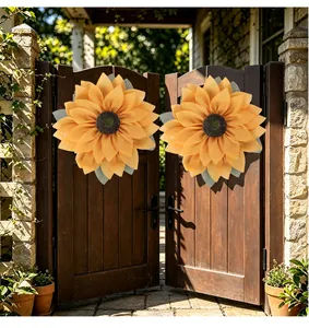 Pair of large yellow fabric sunflower wreaths hanging on a rustic dark wood garden gate.