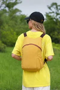 Yellow lightweight hiking daypack shown from rear view in an outdoor setting