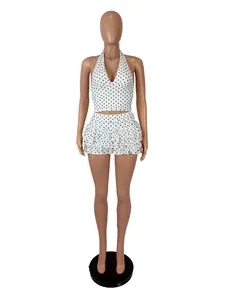 Detailed front view of a two-piece white polka dot halter top and ruffled skirt set