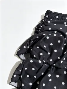 Close-up detail showing texture and tiered ruffles of black skirt with white polka dots