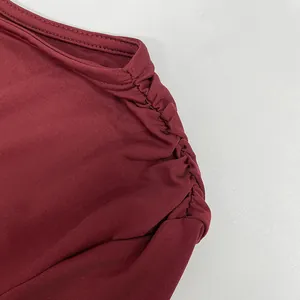 Macro view showing the elegant ruched shoulder detail and ribbed texture of a burgundy dress