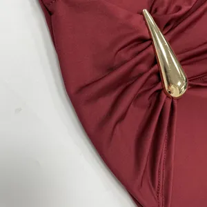Close-up detail of a gold drop-shaped metal buckle on a burgundy elegant formal dress