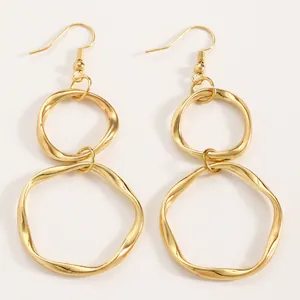 Macro view of minimalist gold-tone irregular double hoop geometric dangle earrings with glossy finish