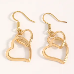 Detail view of golden minimalist interlocking double heart drop earrings on white.