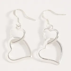 Macro detail view of the elegant interlocking open heart design on silver drop earrings