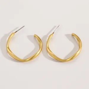 Close-up of matte gold twisted hoop earrings with irregular wave design detail