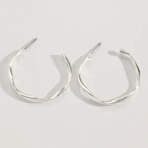 Macro detail of minimalist silver twisted hoop earrings with elegant geometric design
