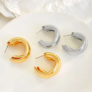 Close-up detail of stylish gold and silver layered hoop earrings on a white plate backdrop