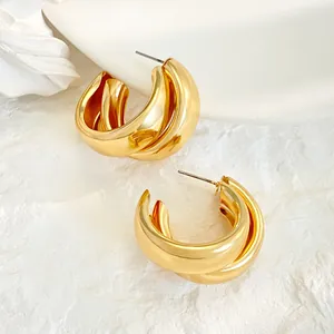Close-up detail of golden chunky triple-layer geometric hoop earrings on white background