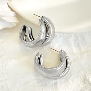 Close-up of modern silver triple-layer C-shaped hoop earrings with polished finish.