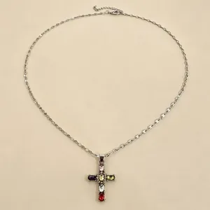 Primo piano dettagliato di una collana d'argento con pendente a croce in cristallo colorato