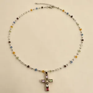 Dettaglio di un ciondolo a croce di cristallo colorato con una collana di perline multicolore