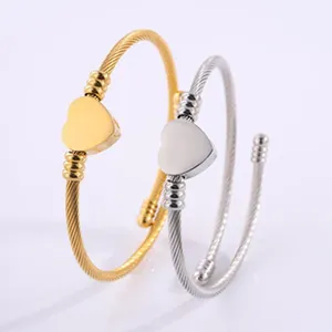 Detailed macro shot of gold and silver twisted cable stainless steel bangles with heart charms